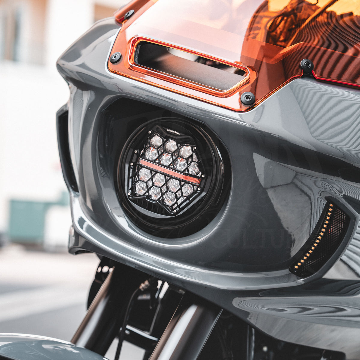 Clear-lens HexBeam Pro headlight installed in a gray motorcycle fairing with an orange windshield.