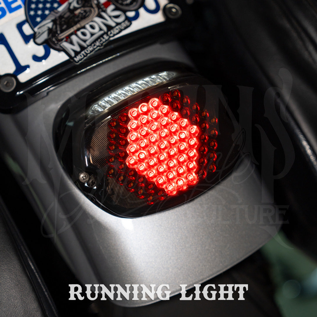 Red running-light pattern on a MOONSMC V4 tail light installed on a motorcycle rear fender.
