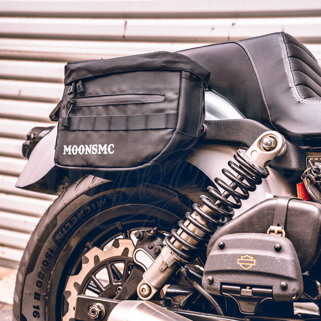 Side view of a MOONSMC RECON saddlebag installed above a motorcycle rear shock.