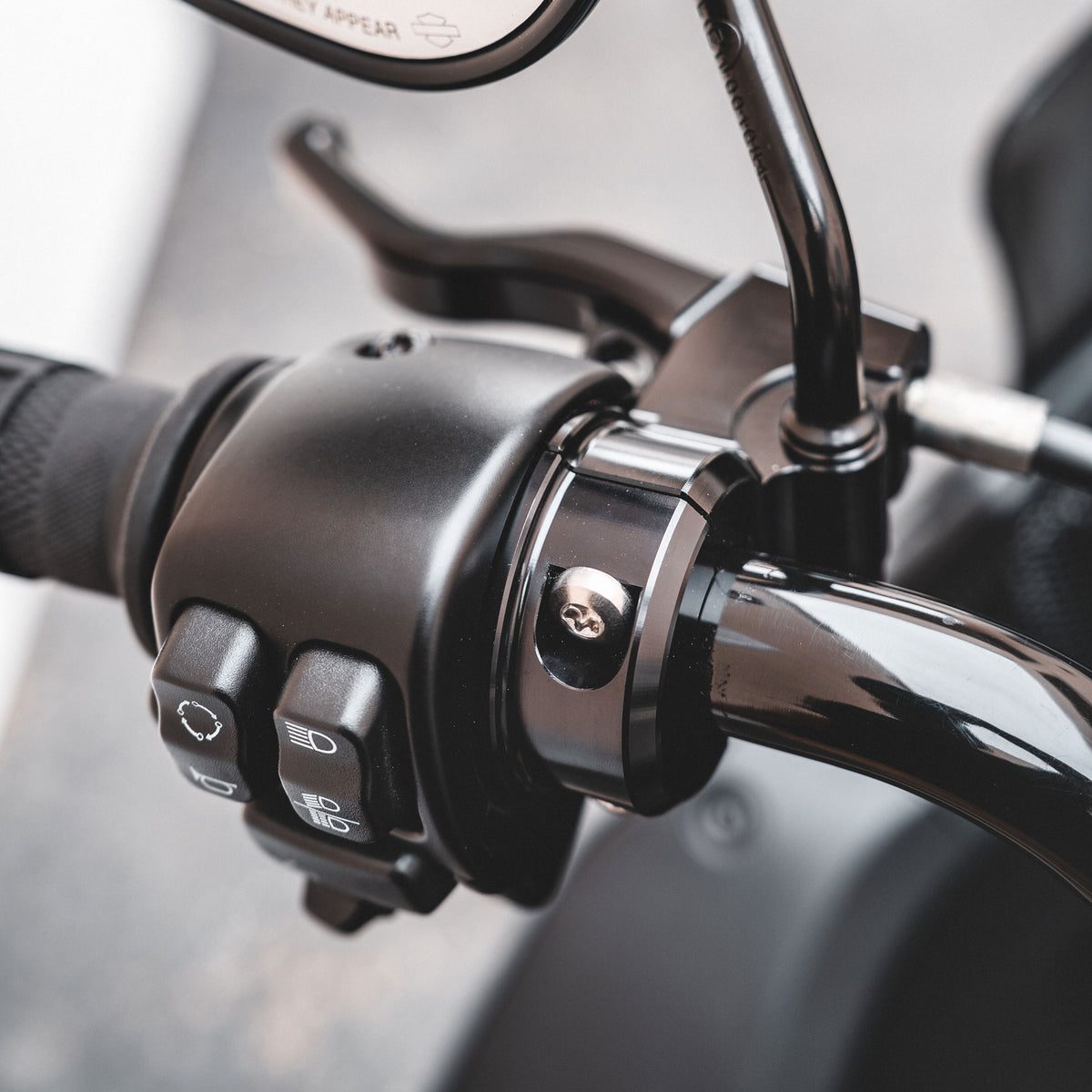 Close-up of the installed MOONSMC Shorty lever pivot beside the motorcycle switch housing.