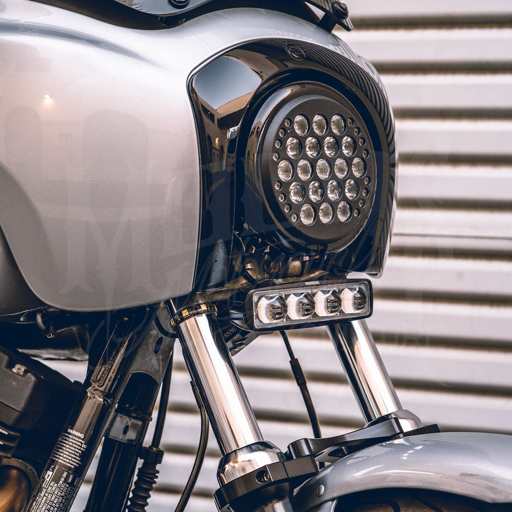 V3 LED light bar mounted beneath a round headlight on a silver motorcycle.