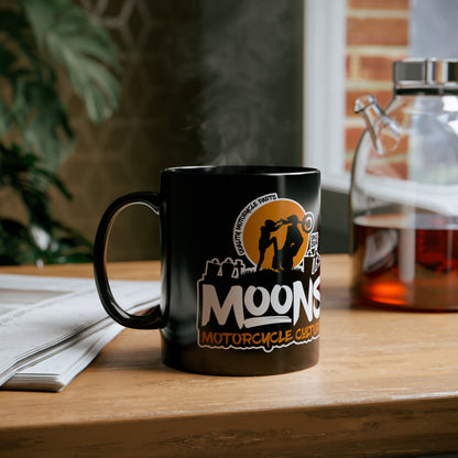 MOONSMC Dyna Graveyard Wheelie 11oz Black Mug: printed black mug on a wooden table beside an open book.