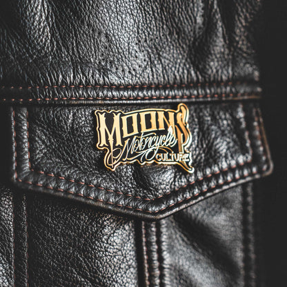 MOONSMC OG Logo Black & Gold Enamel Collector Pin: close-up of the logo pin on a black leather pocket.