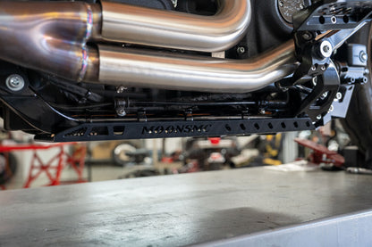 Side view of the installed Softail M8 full lower skid plate beneath the exhaust pipes.