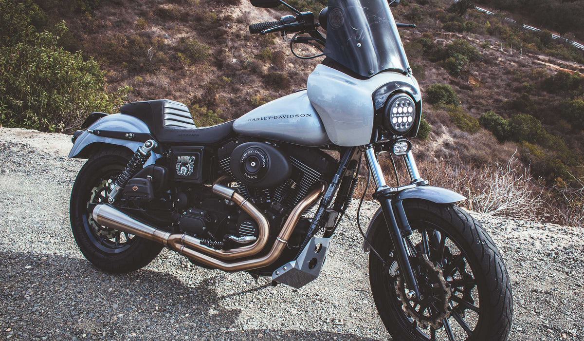 Silver Harley-Davidson Dyna with MOONSMC LED lighting beside a canyon road