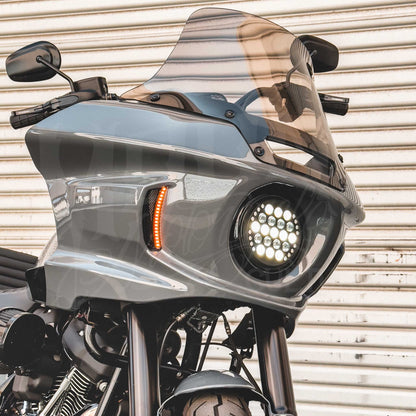Amber FXLRST vent light illuminated beside a round headlight in a gray motorcycle fairing.