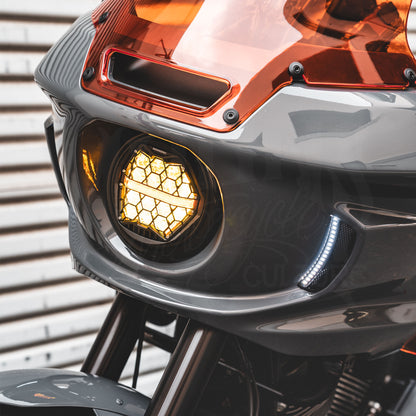 Illuminated amber HexBeam Pro headlight and white running lights on a gray motorcycle fairing.