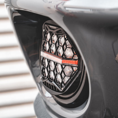Side close-up of the clear-lens HexBeam Pro headlight recessed in a gray motorcycle fairing.