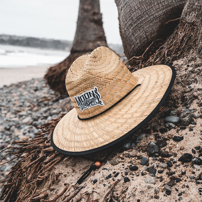 MOONSMC OG Logo UPF 50+ Lifeguard Straw Hat: straw hat leaning against a palm tree at the beach.