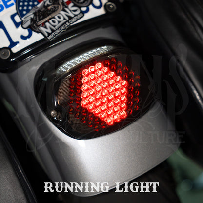 Red running-light pattern on a MOONSMC V4 tail light installed on a motorcycle rear fender.