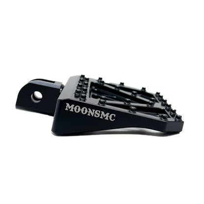 Low side view of a black MOONSMC Softail M8 mini floorboard showing its traction pins.