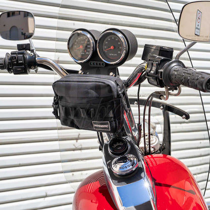 Black MOONSMC UrbanOps bag mounted below the gauges on a red motorcycle's handlebars.
