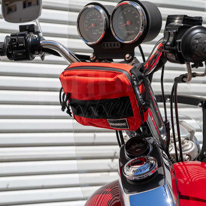 Red MOONSMC UrbanOps bag mounted below the gauges on a red motorcycle's handlebars.