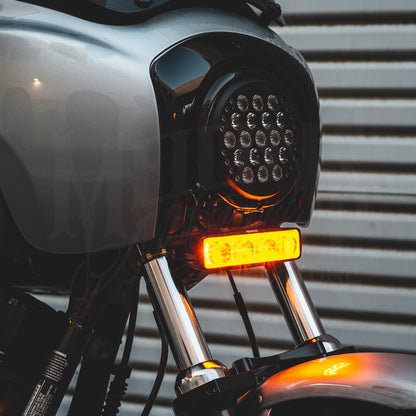 V3 LED light bar illuminated amber beneath a round motorcycle headlight.